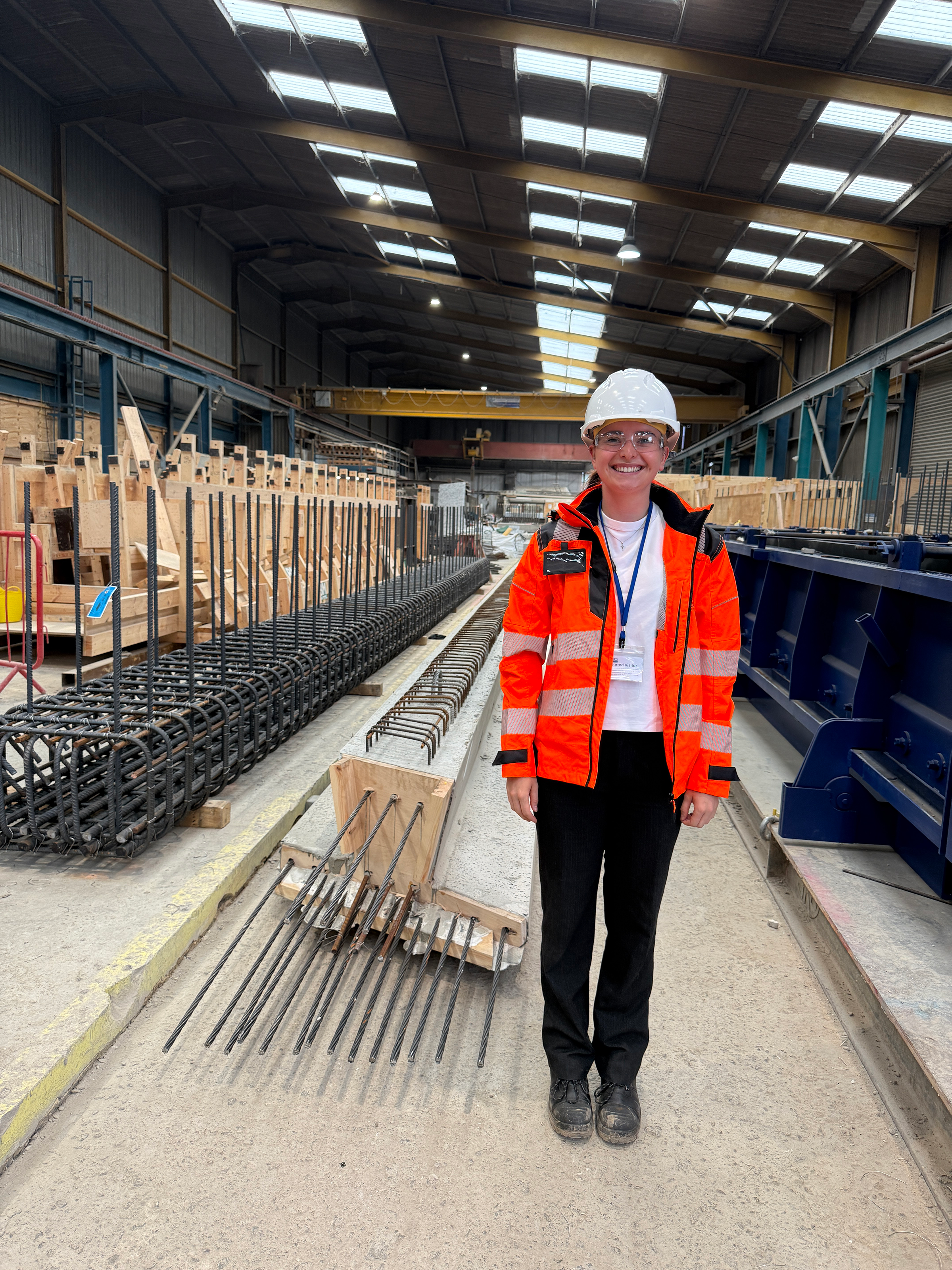 Young woman in an orange high-vis jacket and white hard hat